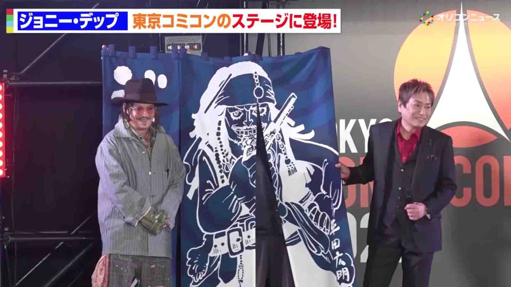 Hiroaki Hirata presents a blue noren curtain to Johnny Depp at Tokyo Comic Con 2025.