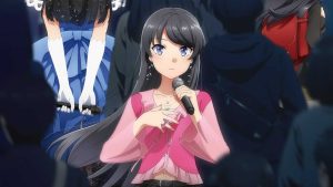 The official key visual for the Rascal Does Not Dream of a Dear Friend movie showing the female protagonist, Mai Sakurajima, holding a microphone amidst a sea of people.