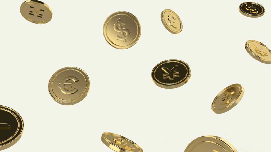 A group of gold coins scattered featuring different currencies dollar, yen, euro, and more.