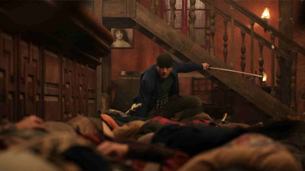 Mackenyu as Zoro posing in the bar fight scene in Loguetown in One Piece live action Season 2 Episode 3, "Whisky Business"