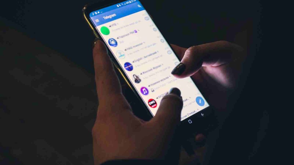 Woman holding phone with Telegram app open buying from Fandom Telegram Channels