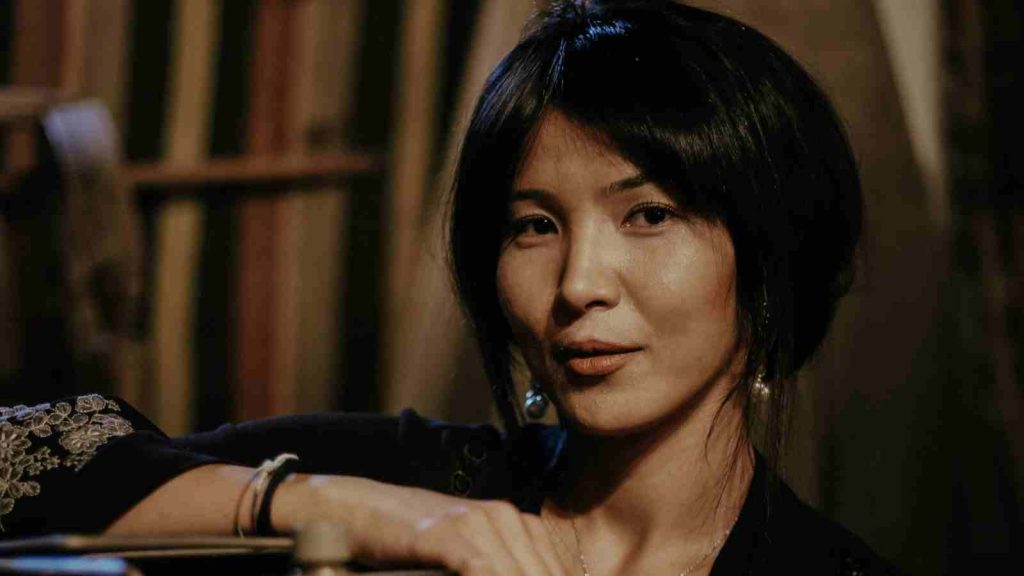 Asian woman poses for the camera with one hand on film projector