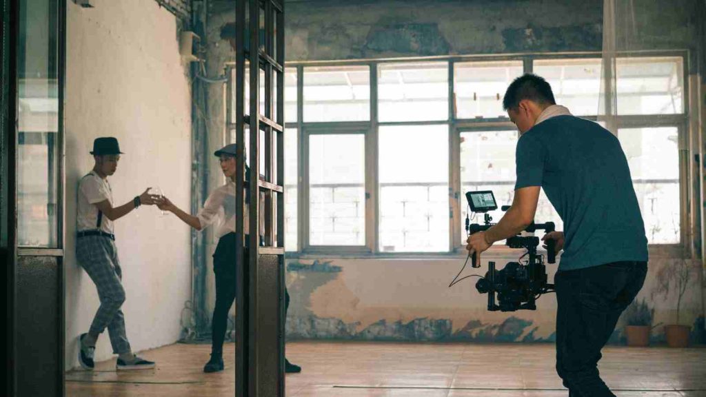 Man filming Asian actor and actress acting in mini drama in run down building