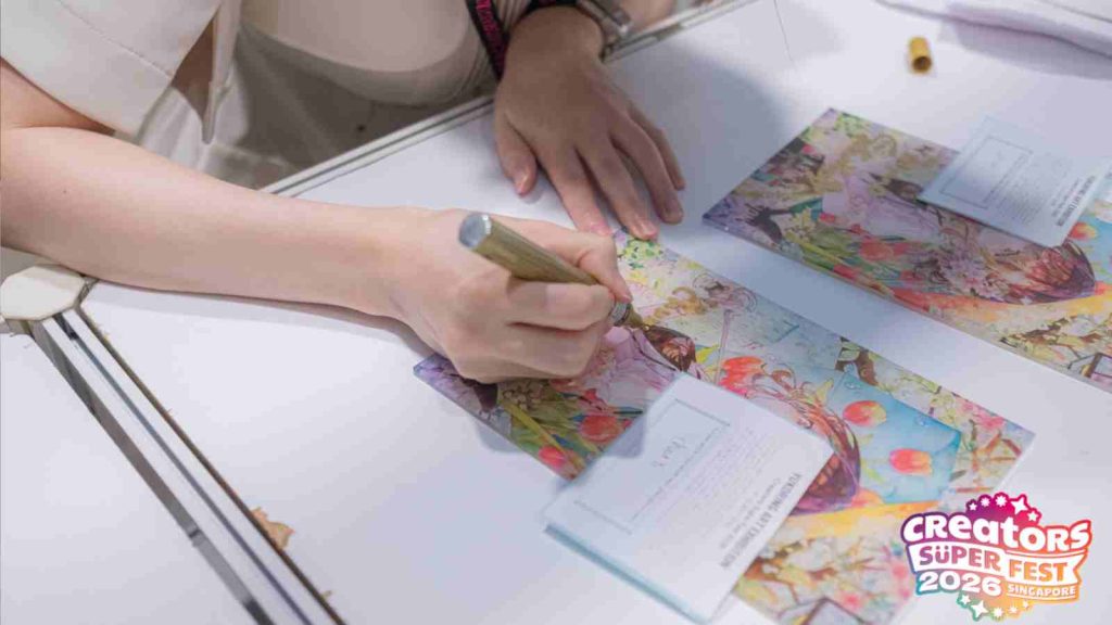 Japanese artist Yukoring signing a print of her watercolor work at an autograph session during AFA CSF 2026