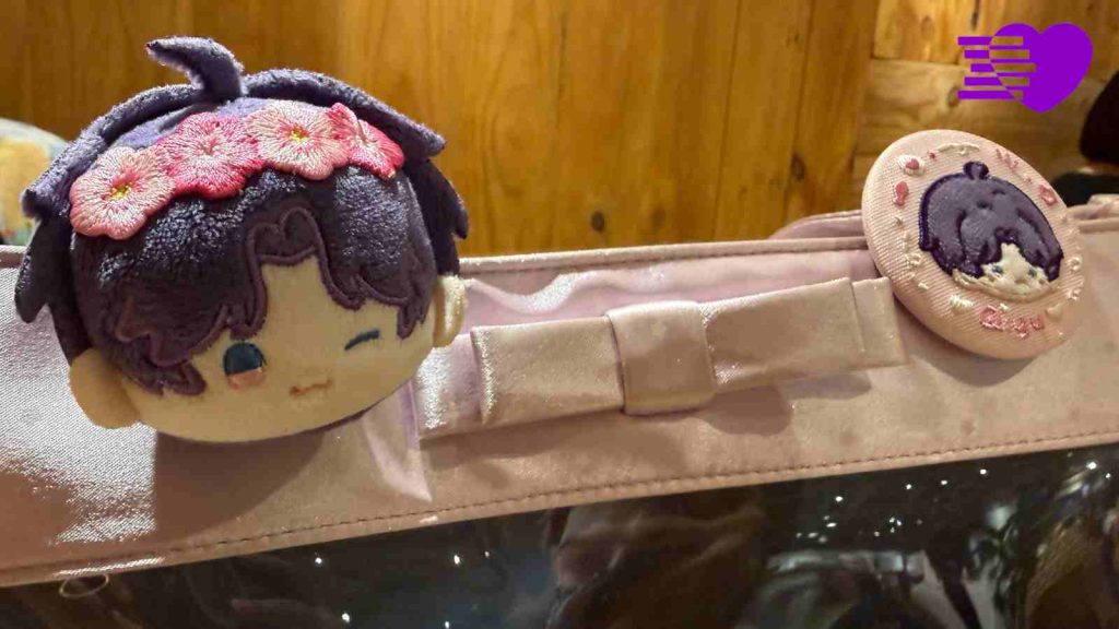 Love and Deepspace's Rafayel doll head pin and official cloth badge pinned on Melissa's handbag
