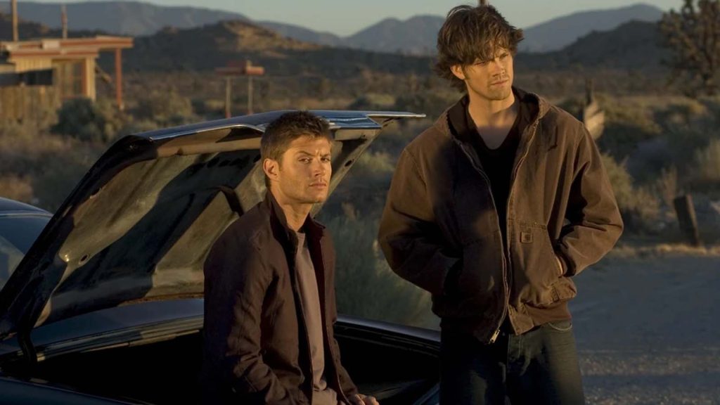 Sam and Dean Winchester, played by Jared Padalecki and Jensen Ackles, in the Supernatural TV series. The two can be seen hanging out around a vehicle.