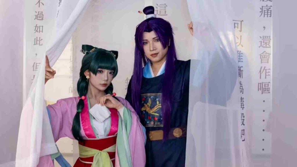 Maomao and Jinshi cosplayers posing with curtains at The Apothecary Diaries Exhibition