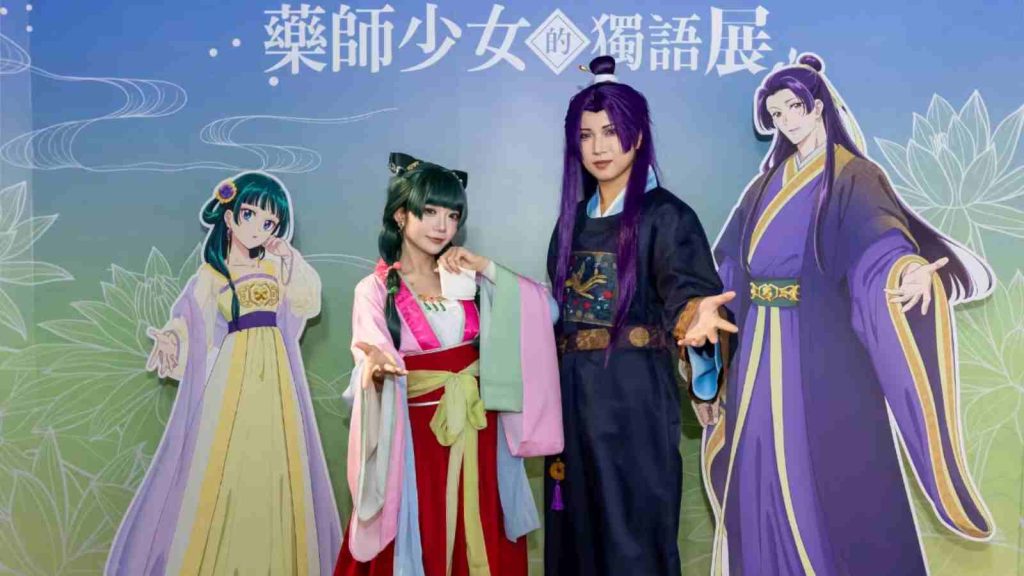 Maomao and Jinshi cosplayers posing with their character standees at The Apothecary Diaries Exhibition